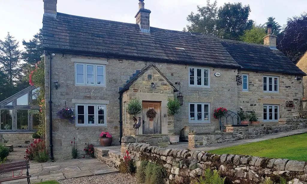 Cottage styled home with green casement windows